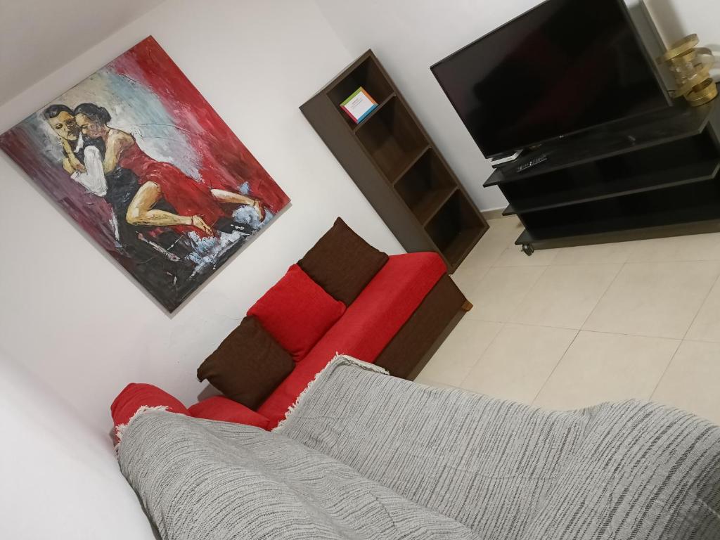 a living room with a red couch and a tv at Tarancon Suite Exclusivo in Tarancón