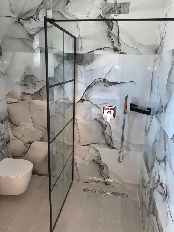 bagno con servizi igienici e parete in marmo. di Vila Elite a Ksamil