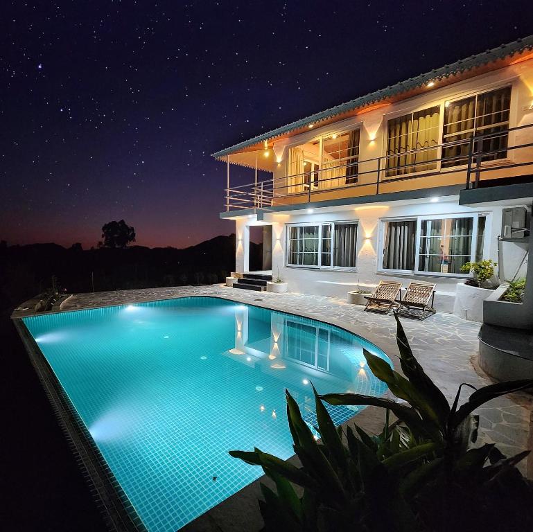 una piscina frente a una casa por la noche en The Riverside Estate - 2Bedroom Private Pool Villa in Udaipur en Udaipur