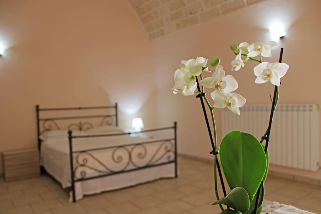 um quarto com uma cama e um vaso com flores brancas em Le 3 volte/ Antica dimora em Spongano