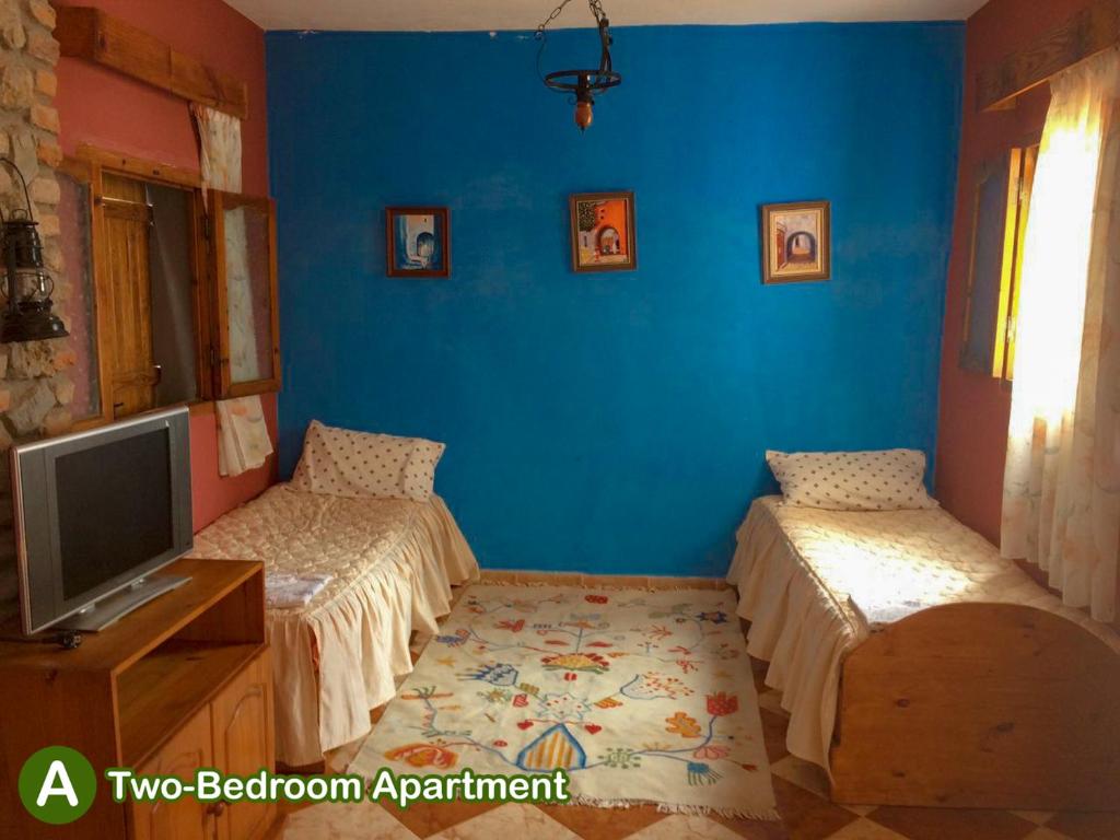 a blue room with two beds and a television at dar zaiouane in Berga