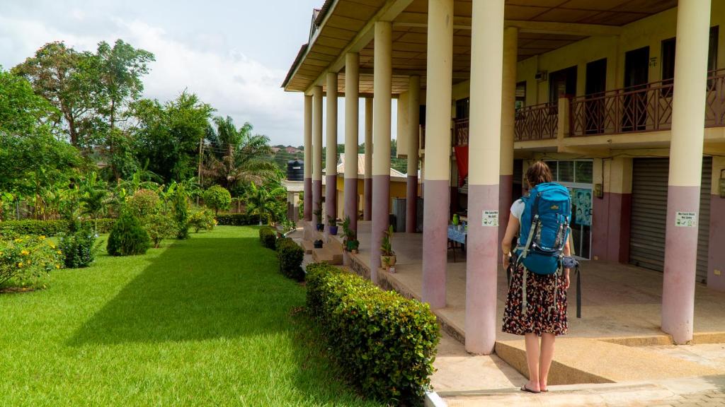 a woman with a backpack standing outside of a building at Sign of Silence Hostel in Kumasi