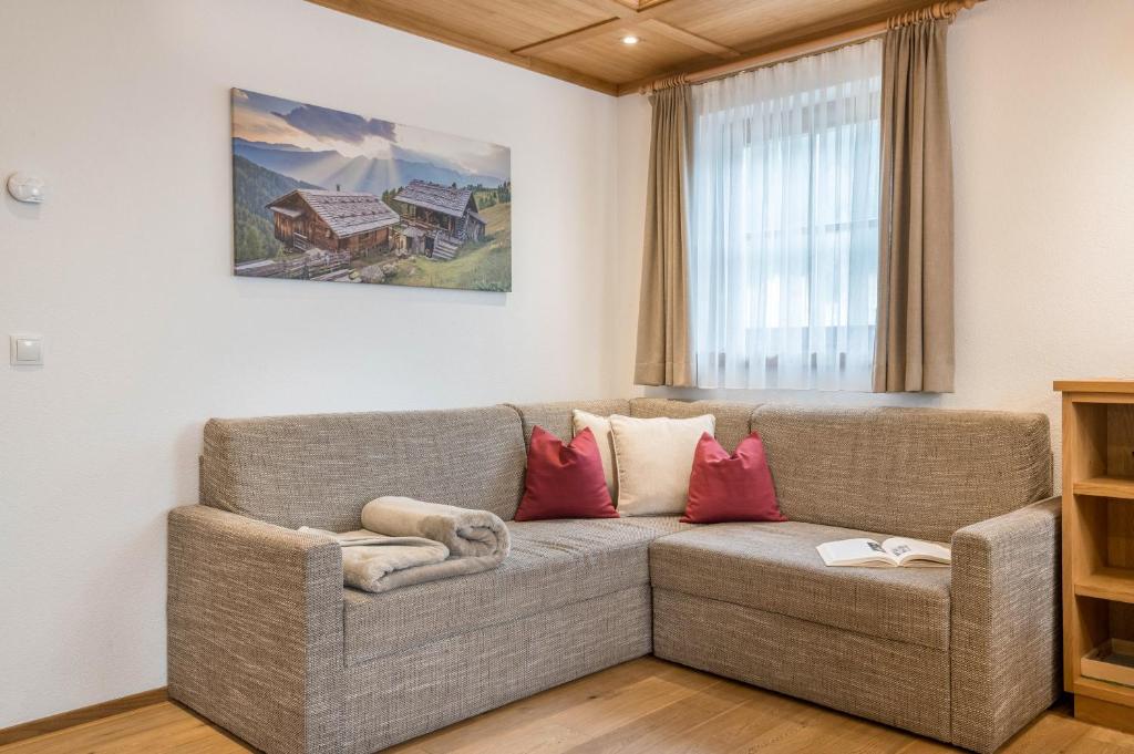 a living room with a gray couch with red pillows at Feldererhof Apt Hochstein in Santa Maddalena