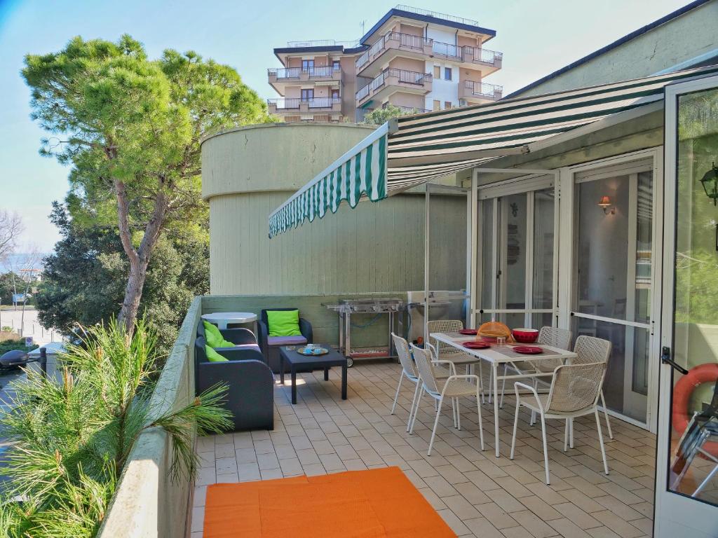 d'une terrasse avec une table et des chaises sur un balcon. dans l'établissement Beach Kite 8 posti letto - Terrazzo e parcheggio, à Grado-Pineta