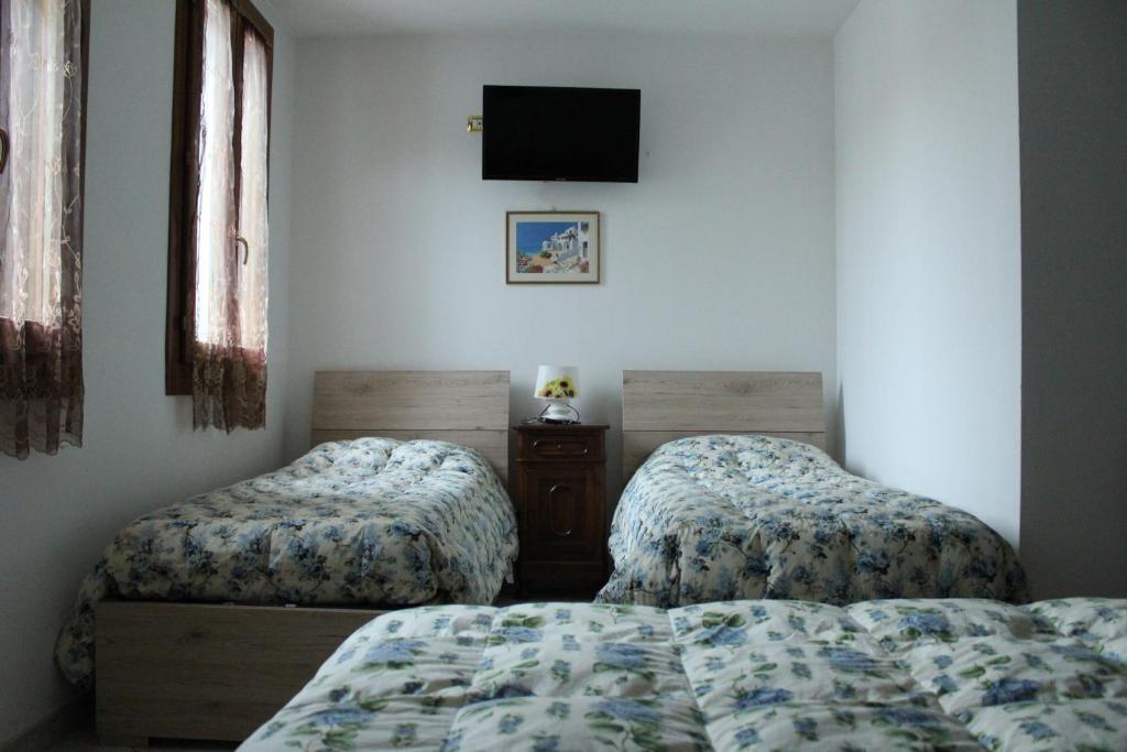 1 dormitorio con 2 camas y TV en la pared en Locanda della Pescheria en Comacchio
