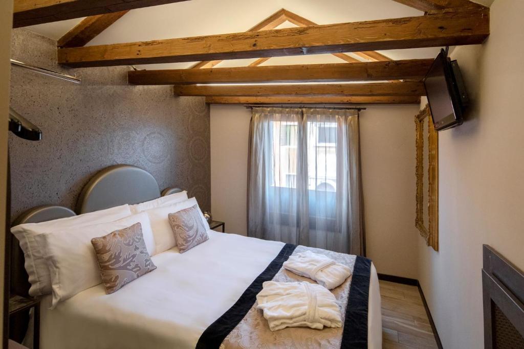 a bedroom with a white bed with a window at Alle Guglie Boutique Hotel in Venice