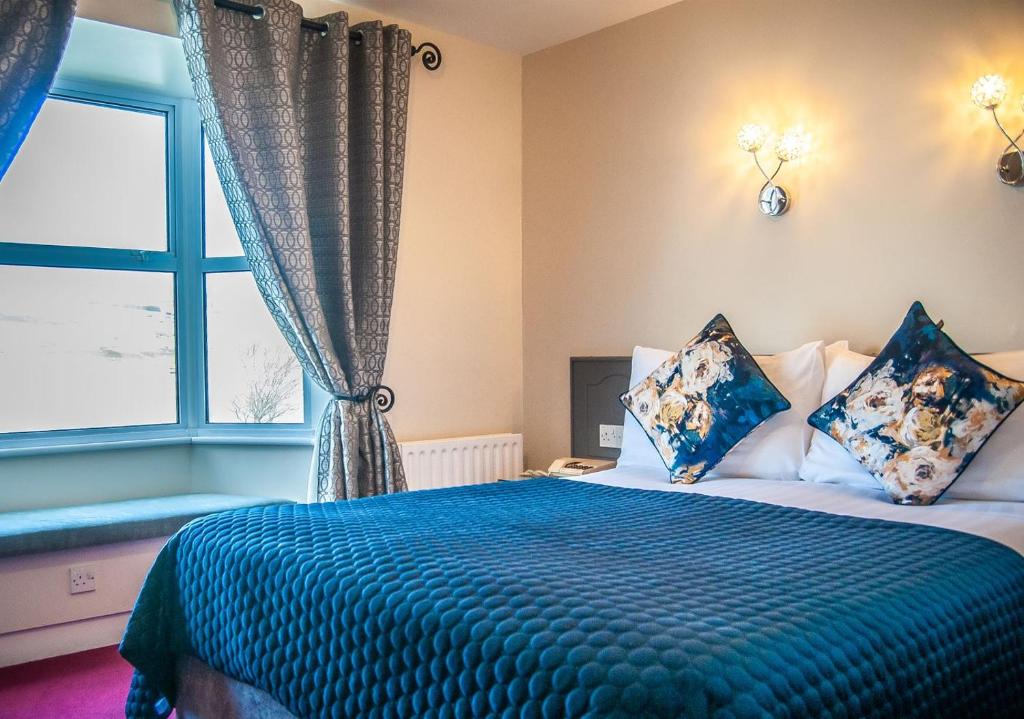 a bedroom with a bed with a blue blanket and a window at Arnolds Hotel in Dunfanaghy