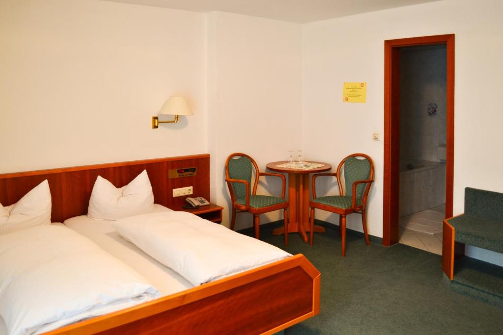 - une chambre avec un lit, une table et des chaises dans l'établissement Landgasthof mit Gästezimmer Frohe Einkehr, à Fribourg-en-Brisgau