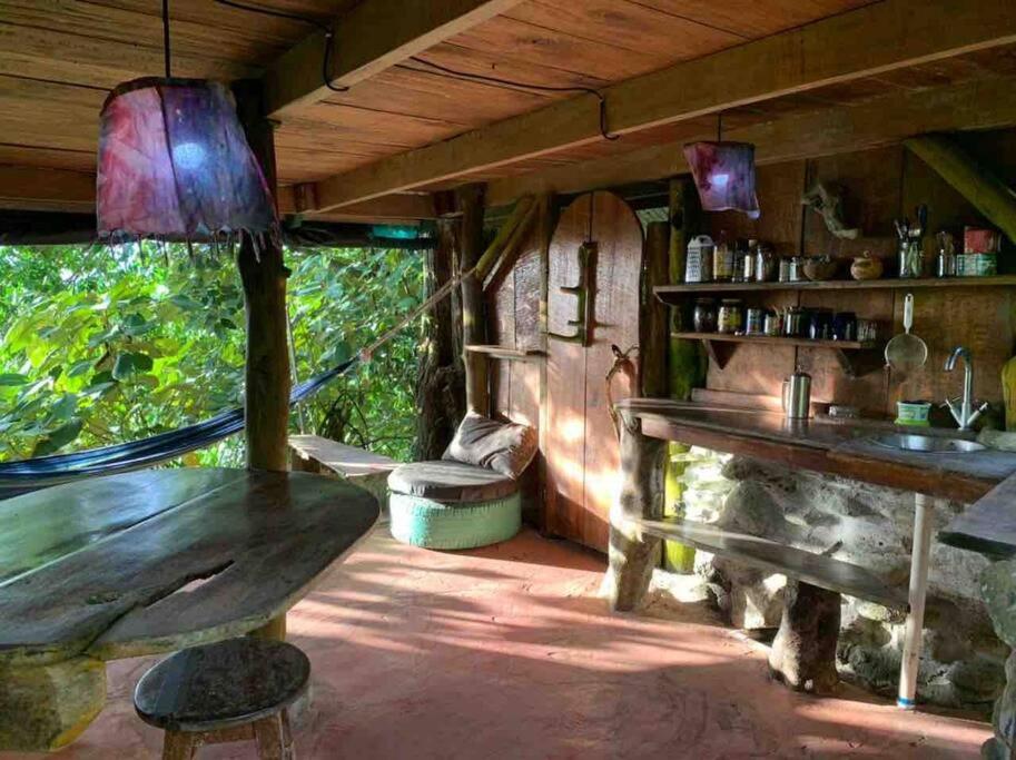 a dining room with a table and a stone fireplace at Ocean View rustic cabin in the jungle by the surf in Pavones