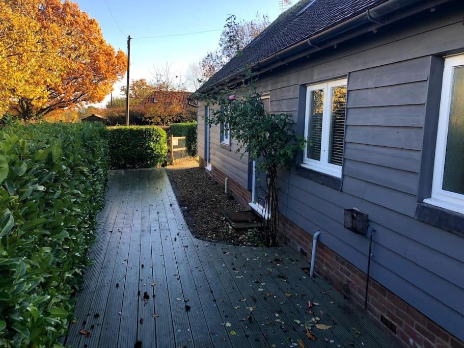 a house with a wooden walkway next to a house at Converted Countryside Barn in Inkpen