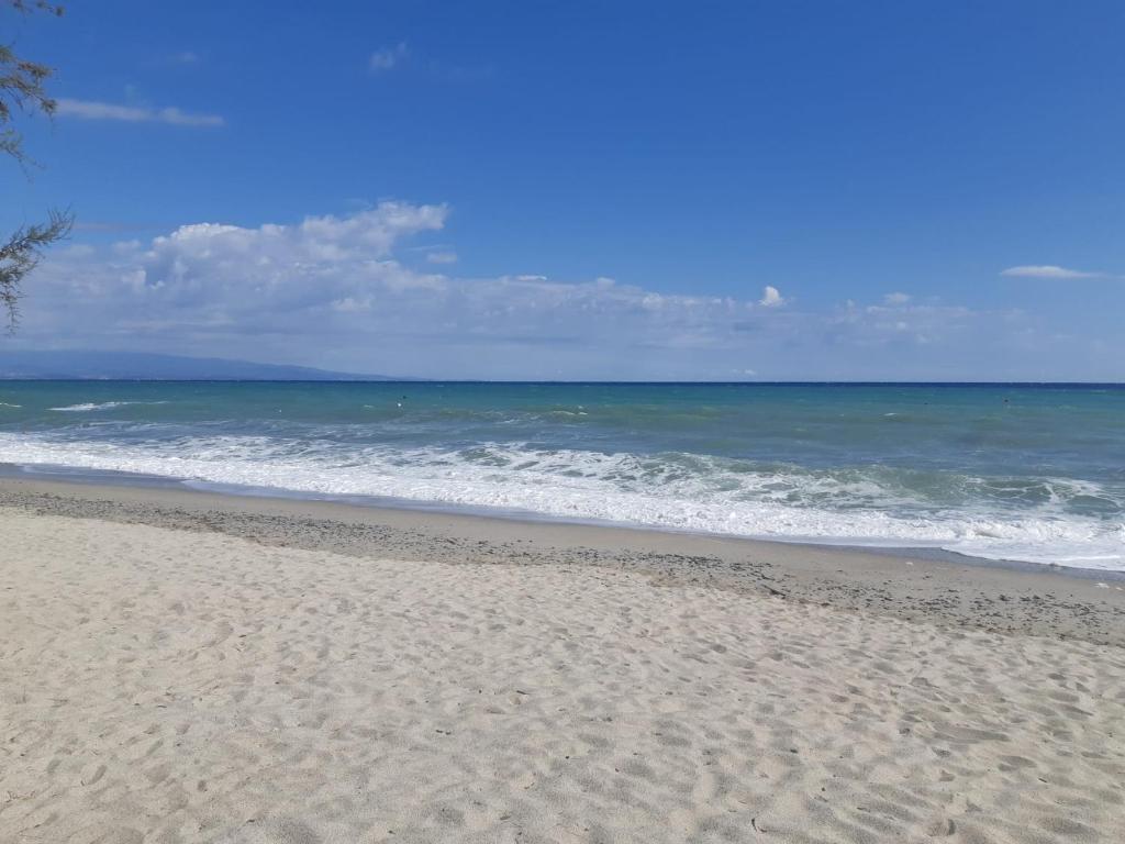 una playa de arena con el océano en el fondo en SERENA SWEET HOUSE, en SantʼAndrea Apostolo dello Ionio