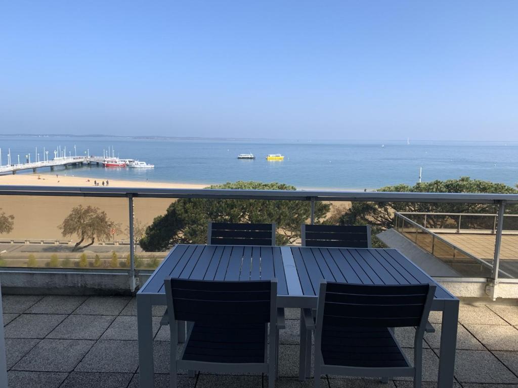 - une table bleue et des chaises sur un balcon donnant sur la plage dans l'établissement Appartement T2 au centre d'Arcachon avec balcon vue bassin et parking - FR-1-374-51, à Arcachon