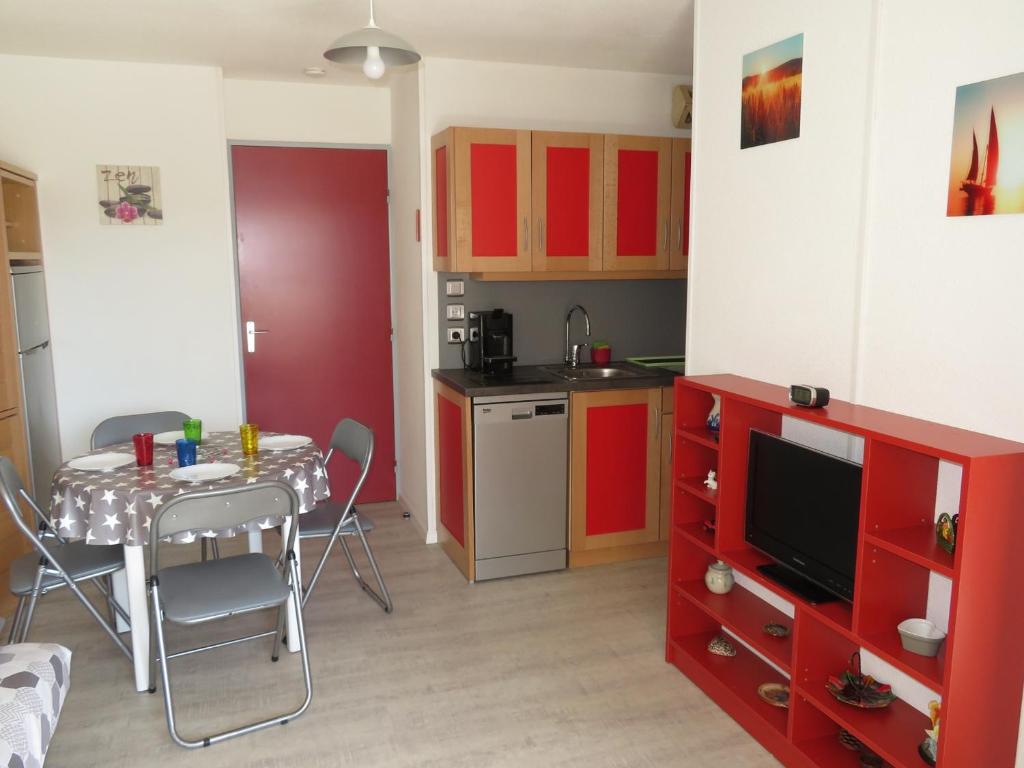 a kitchen with red cabinets and a table with a television at Appartement Sète, 2 pièces, 4 personnes - FR-1-338-136 in Sète