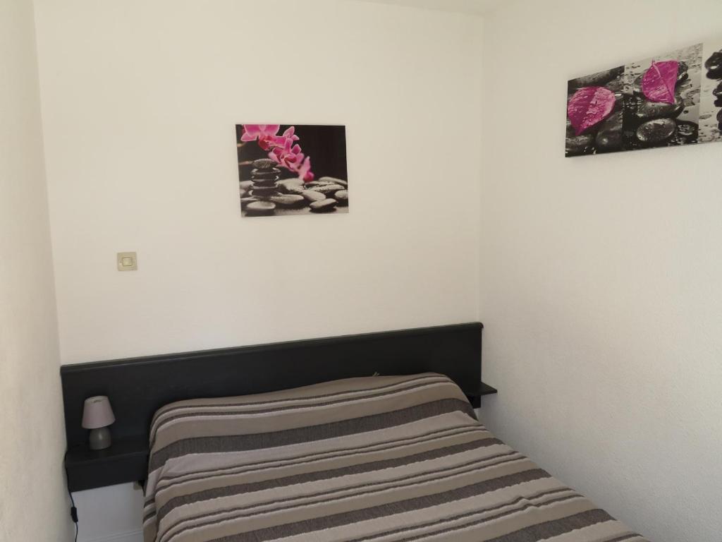a bed in a room with two pictures on the wall at Appartement Sète, 2 pièces, 4 personnes - FR-1-338-136 in Sète