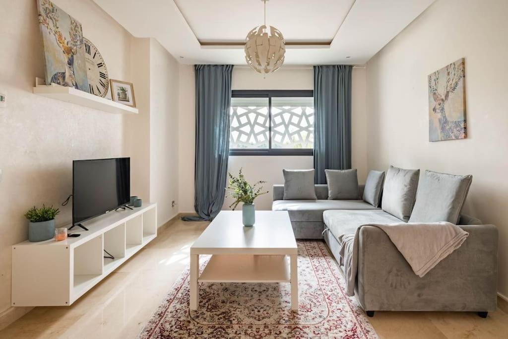 uma sala de estar com um sofá e uma televisão em Lovely Appartement Prestigia Hayriad em Rabat