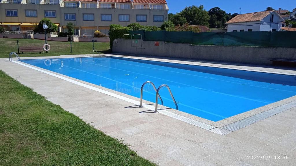a large swimming pool with blue water in a yard at CHALET CON PISCINA EN MIÑO-Perbes in Miño