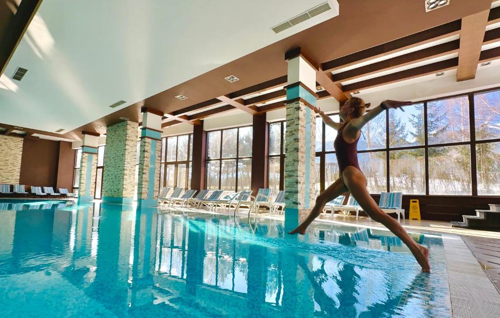 a woman is jumping into a swimming pool at Terra Hotel in Bansko