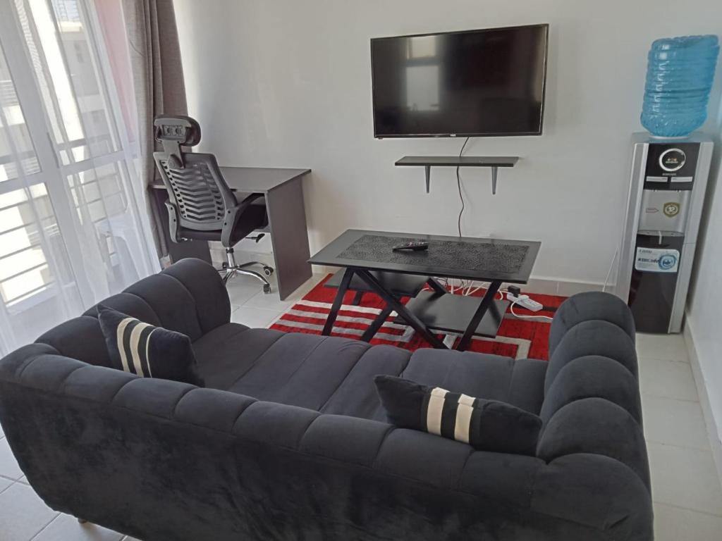 a living room with a black couch and a tv at Ngong Road Studio in Nairobi