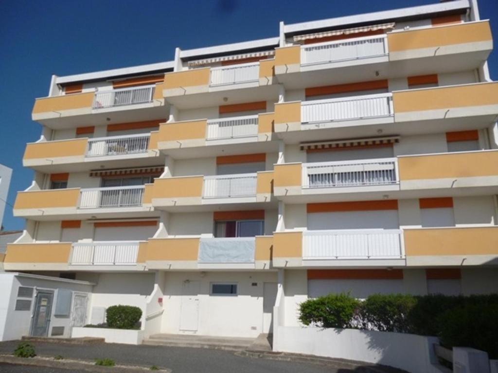 un grand immeuble avec des balcons blancs et jaunes dans l'établissement Appartement lumineux Centre Royan proche plage avec parking - FR-1-71-62, à Royan