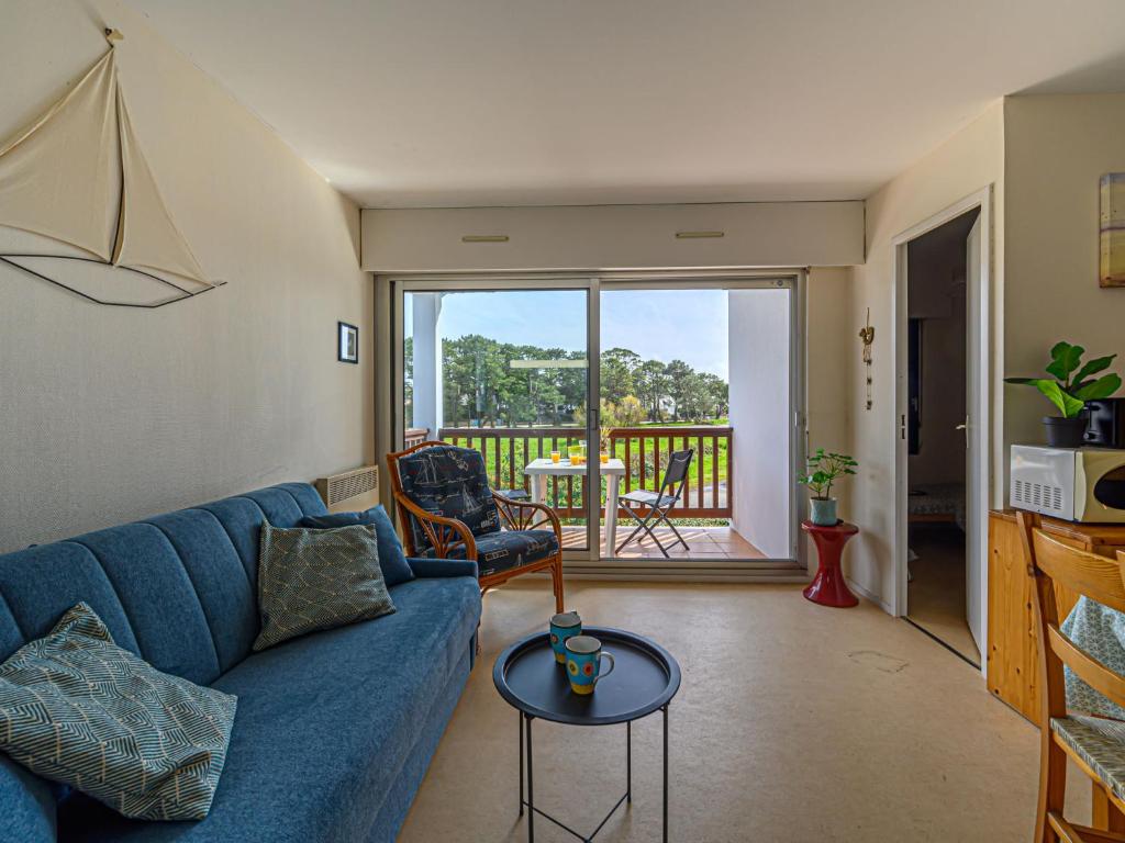 a living room with a blue couch and a balcony at Apartment Plein Ciel-1 by Interhome in Carnac-Plage