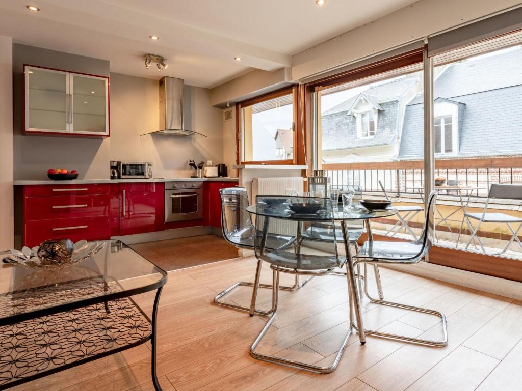 une cuisine avec des placards rouges et une table en verre dans l'établissement Apartment Les Cigognes by Interhome, à Deauville