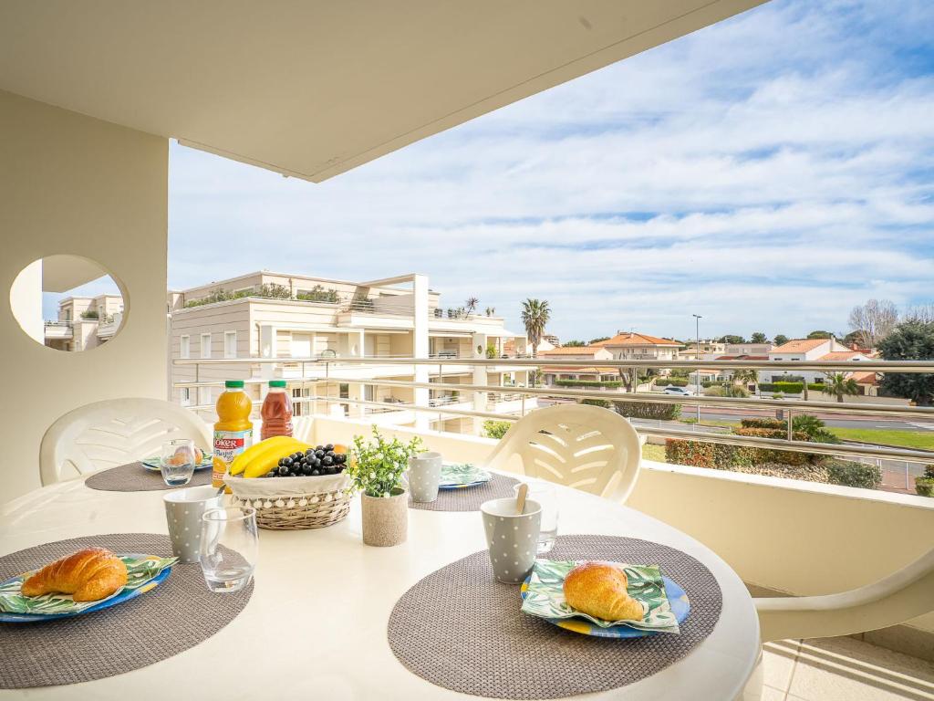 une table avec deux assiettes de nourriture sur un balcon dans l'établissement Apartment Les Néréides by Interhome, à Canet