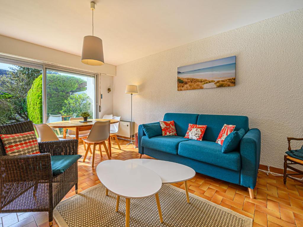 un salon avec un canapé bleu et une table dans l'établissement Apartment La Sauvagère-2 by Interhome, à Carnac