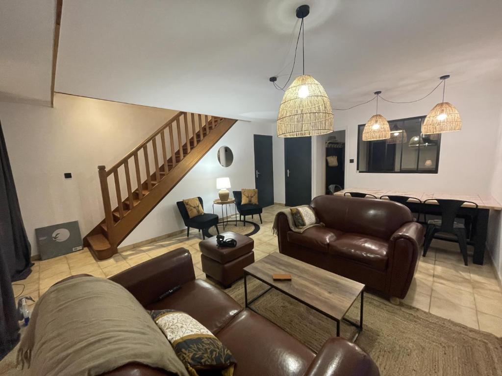 a living room with leather couches and a staircase at Gite du vieux Morat in Saint-Bonnet-Tronçais