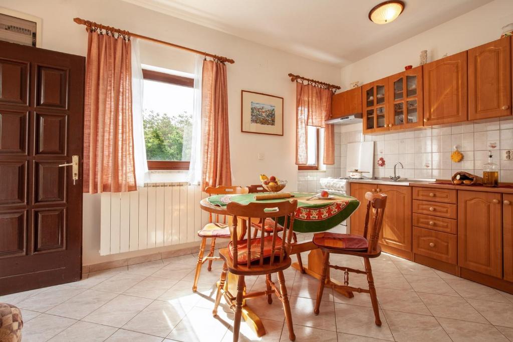 eine Küche mit einem Tisch und Stühlen sowie einem Fenster in der Unterkunft Apartments Jadranka in Medulin