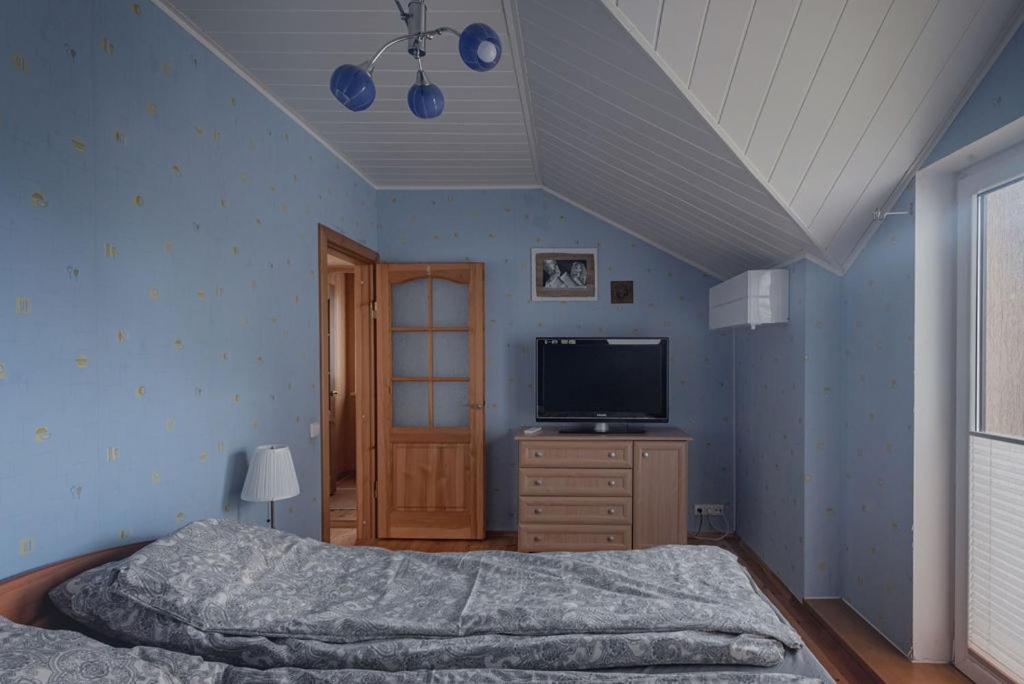 1 dormitorio con cama y vestidor con TV en House Perkūno al 59B, en Kaunas