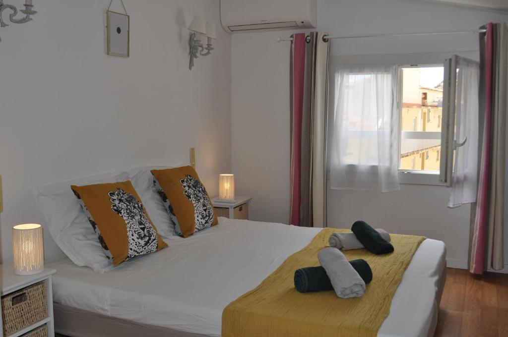 um quarto com uma cama branca com almofadas e uma janela em Appartement duplex plein sud sur le port de Bonifacio em Bonifacio