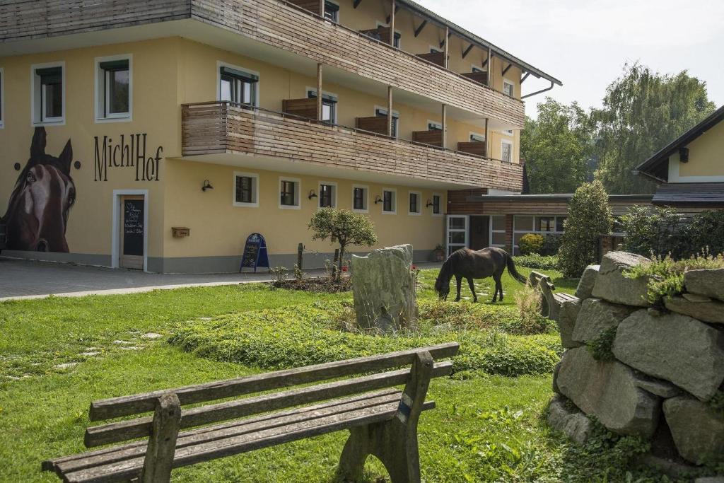 een paard dat graast voor een gebouw met een bank bij Michlhof in Zeil