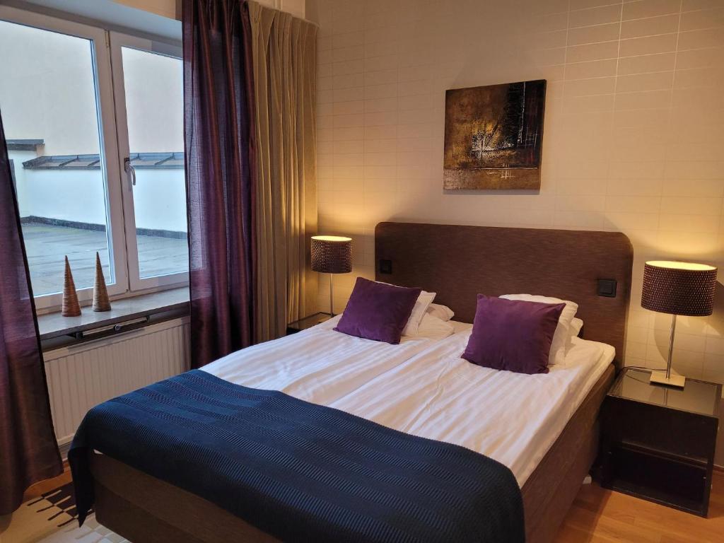 Un dormitorio con una cama con almohadas moradas y una ventana en Stay Apartment Hotel, en Karlskrona