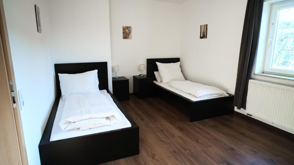 two beds in a room with white sheets at Mivano-Apartments WiFi Küche NETFLIX in Celle