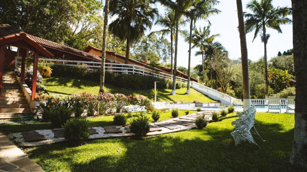 un jardín con palmeras y una casa en Pousada Boutique Mercedes, en Extrema