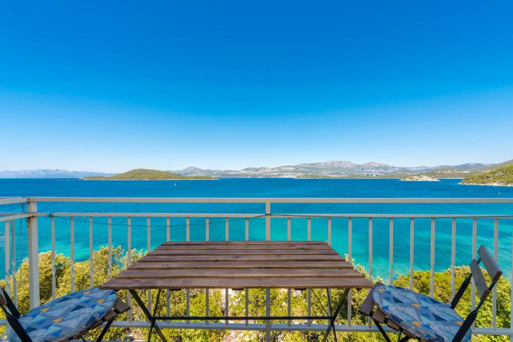 a table and chairs on a balcony overlooking the water at Apartmani Ivušić in Dubrava