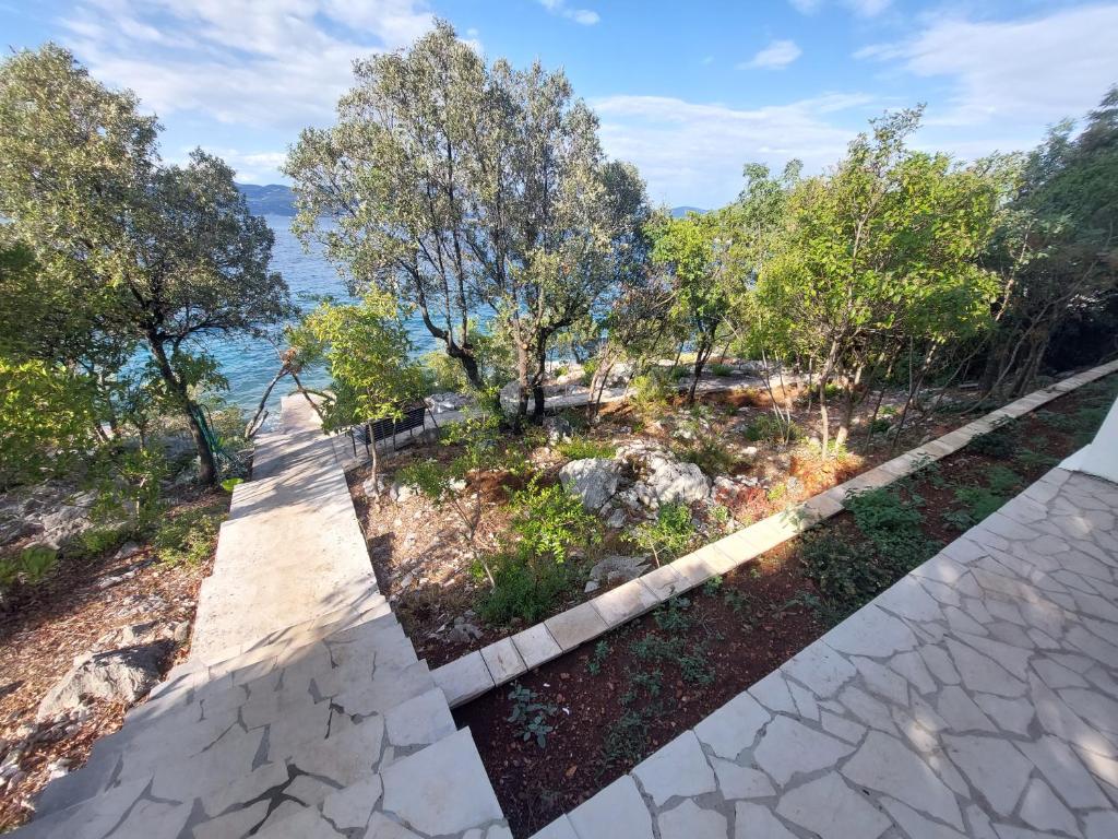a walkway with trees and the ocean in the background at Apartmani Ivušić in Dubrava