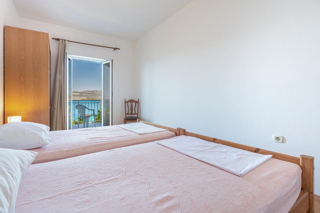 two beds in a bedroom with a view of the ocean at Apartmani Ivušić in Dubrava