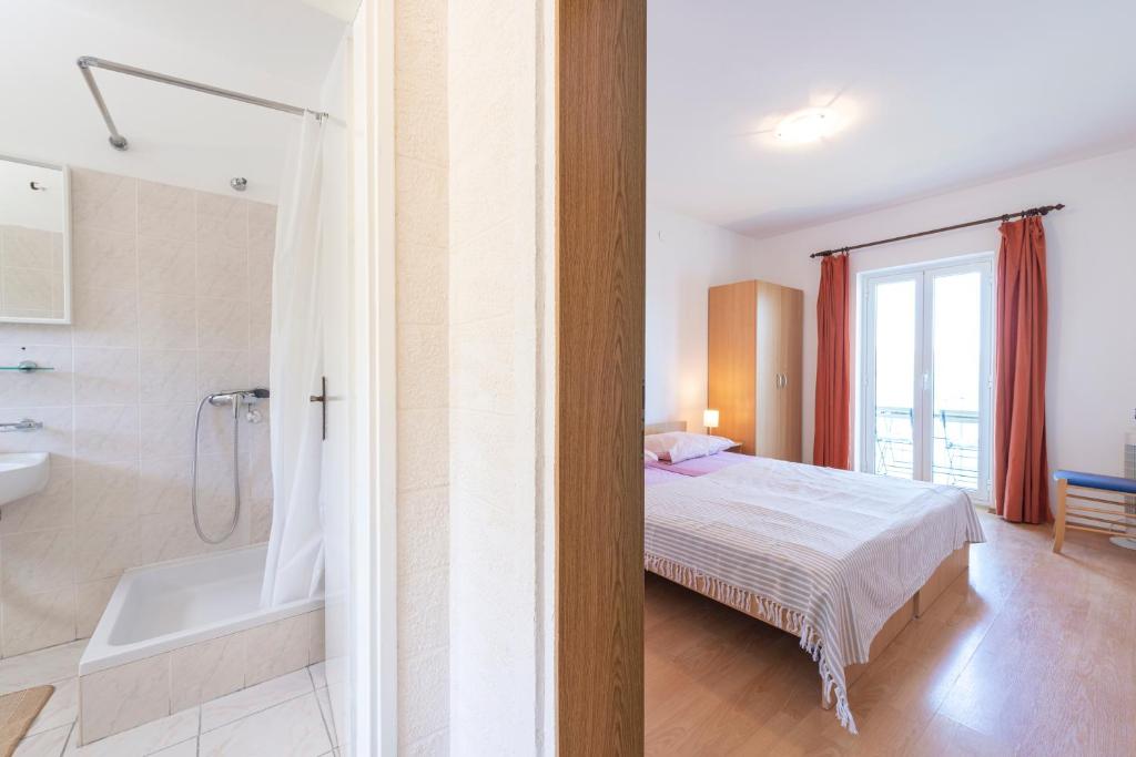 a bedroom with a bed and a tub and a shower at Apartmani Ivušić in Dubrava