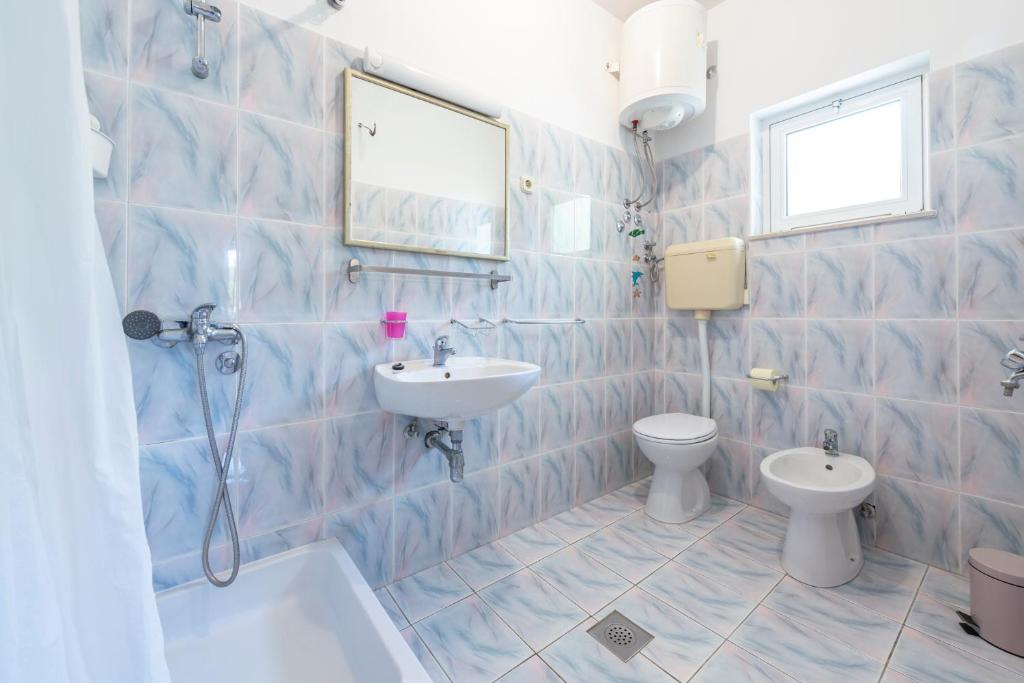 a blue tiled bathroom with a sink and a toilet at Apartmani Ivušić in Dubrava