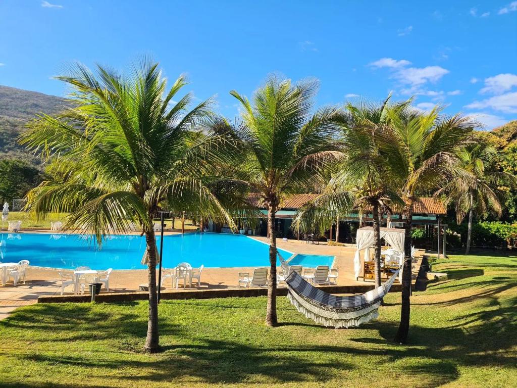 een hangmat tussen twee palmbomen naast een zwembad bij Águas de Santa Bárbara Resort Hotel in Fábrica Santa Bárbara
