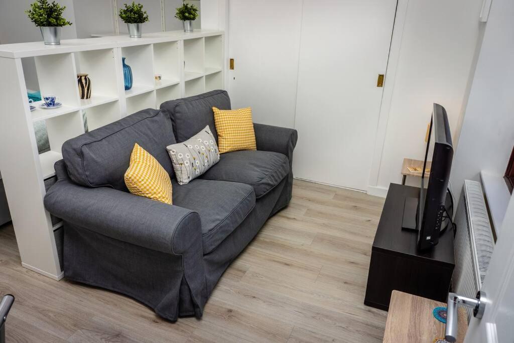 a living room with a gray couch with yellow pillows at Modern bright studio apartment in south Glasgow in Glasgow