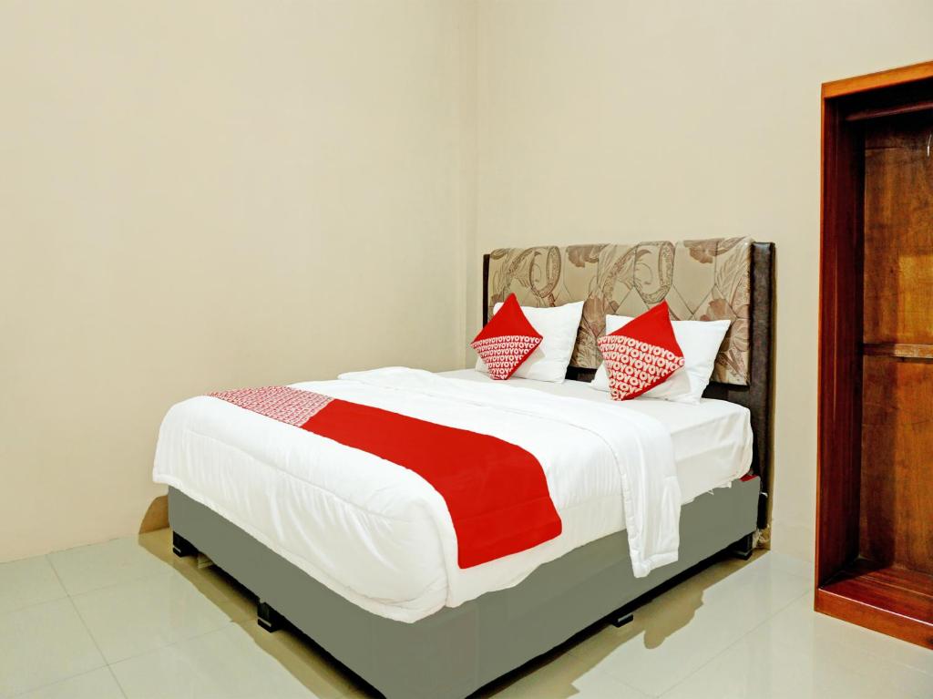 1 dormitorio con 1 cama grande con almohadas rojas y blancas en OYO 92386 Homestay Juwita Perdana Syariah, 