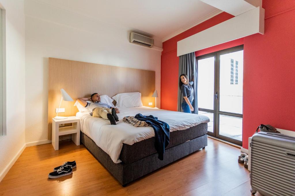 a man laying on a bed in a hotel room at Stay Hotel Coimbra Centro in Coimbra