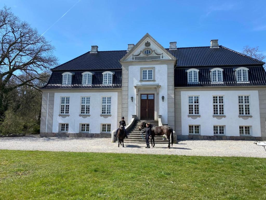 una persona en un caballo delante de una casa en Rosenlund Gods - kælder B&B en Sakskøbing