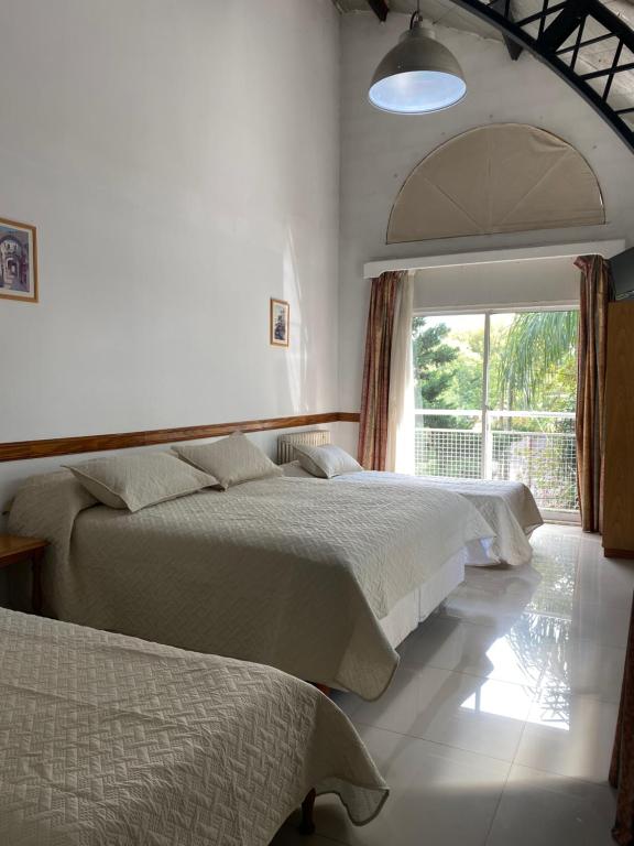 a bedroom with two beds and a large window at Apart Bosch House in Vicente López