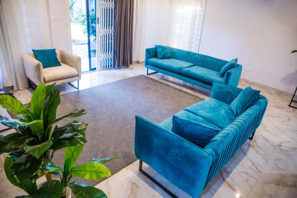 a living room with two blue couches and a plant at Blue Agave F1 in Lusaka