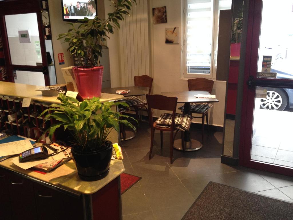 uma sala com mesas e cadeiras e vasos de plantas em Hôtel de l'Europe em Paris