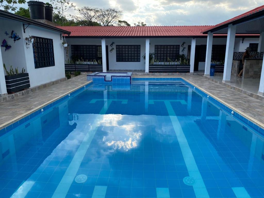 a blue swimming pool in front of a house at Cabañas Villa Albita in Villavicencio