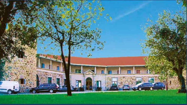 un grand bâtiment avec des voitures garées devant lui dans l'établissement Palace Hotel & Spa Termas de São Tiago, à Penamacor